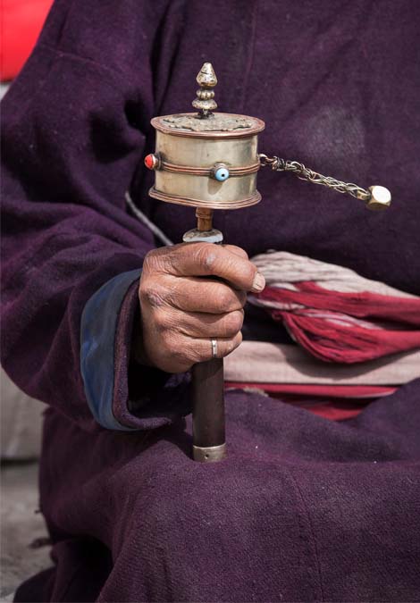 Tibetan monk spinning prayer wheel during daily spiritual practice and meditation