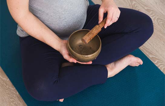 Pregnant woman playing a Tibetan singing bowl during meditation