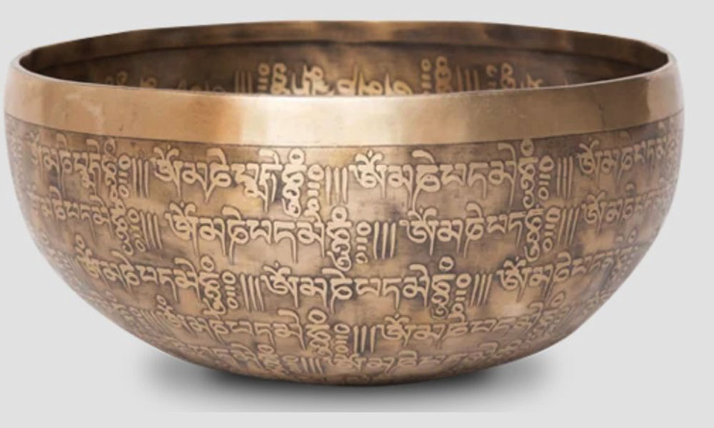 Singing bowl for home decor featuring carved mantras and sacred figures with cultural and artistic value