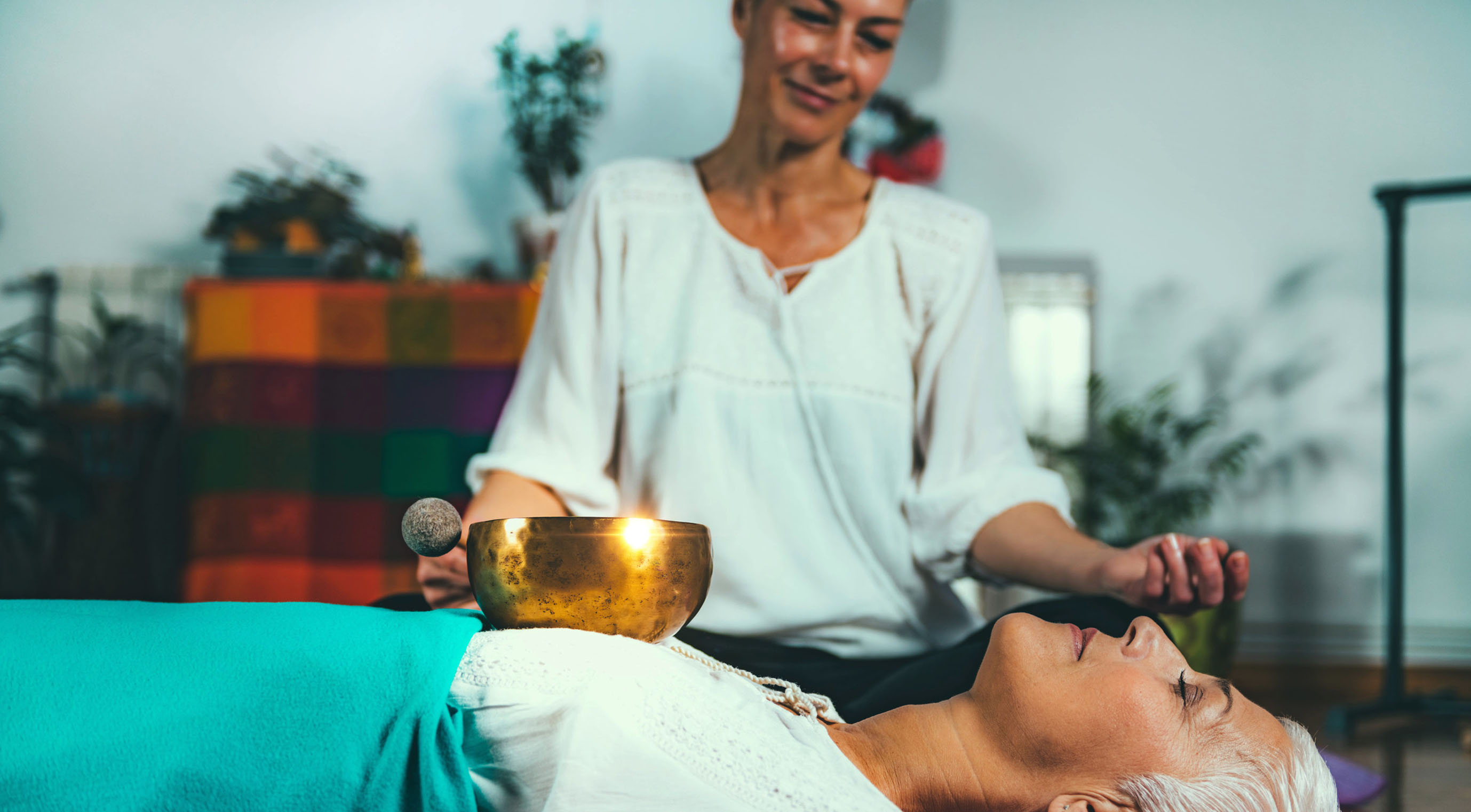 Sound practitioner placing a Tibetan singing bowl directly on a client's body during a vibration therapy session