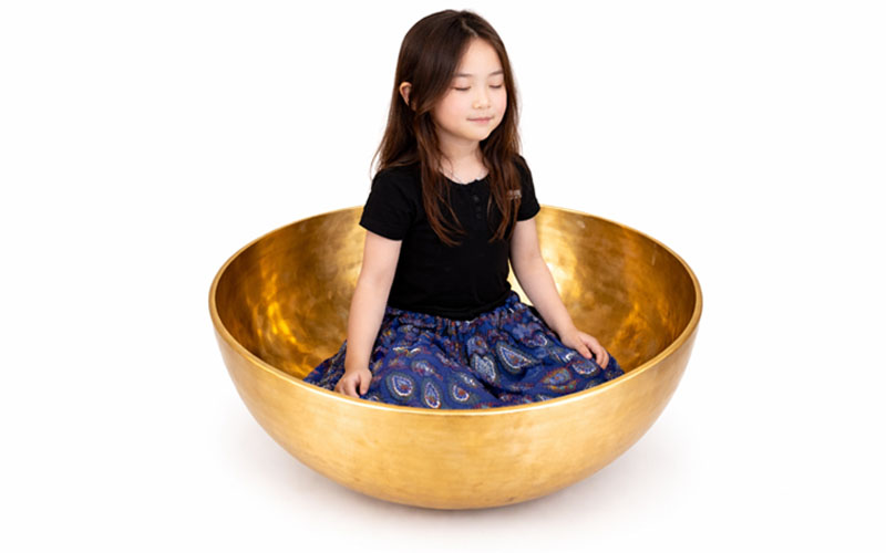 Woman Sitting Inside Large Tibetan Singing Bowl for Full Body Sound Healing and Grounding Energy