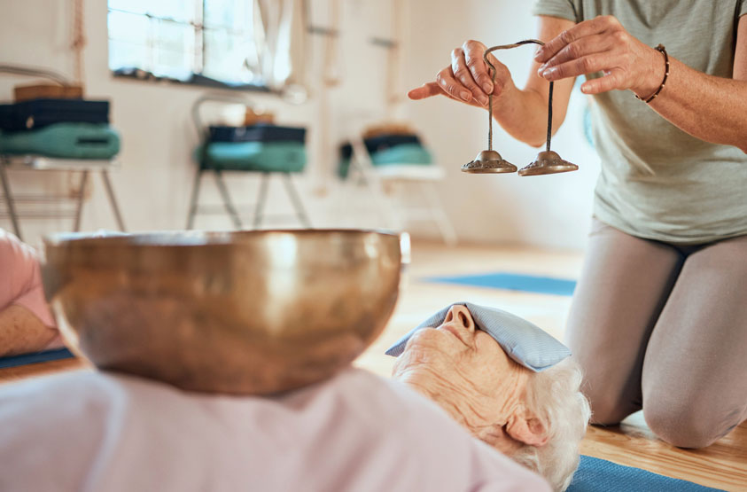 Senior woman enjoying Tibetan singing bowl sound healing session