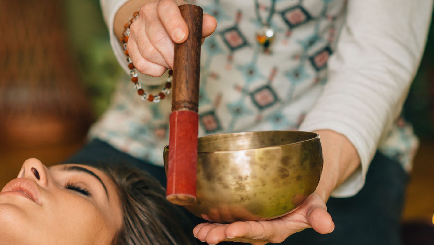 Using wooden mallet on singing bowl